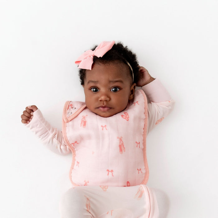 Baby wearing a pink ballerina outfit with matching ballerina bib