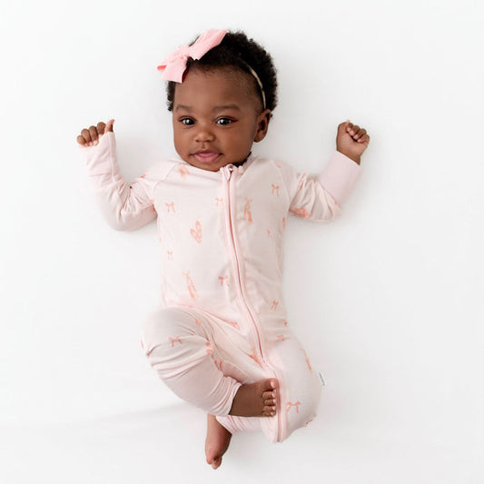 Baby wearing a pink romper with a ballerina print