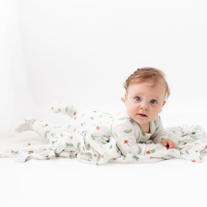 Baby in bird of paradise footie pajama, seated lifestyle shot