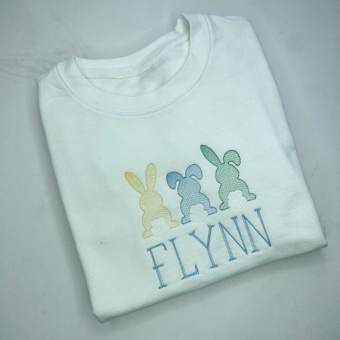 3 bunnies embroidered onto a white sweatshirt in green Lemon and blue