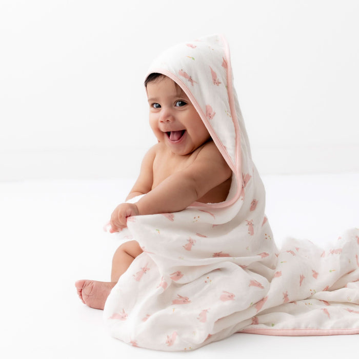 Baby wrapped in a white blanket with pink bunny pattern on a white background