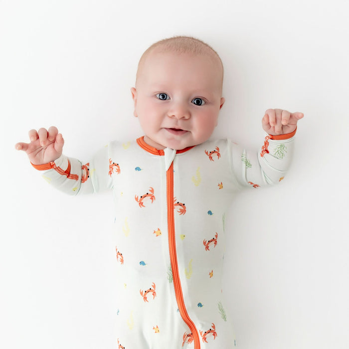 Baby wearing a footie made from bamboo viscose with a crab print