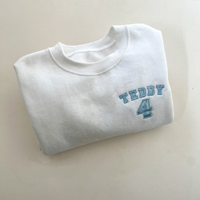 Folded up with jumper with blue embroidery