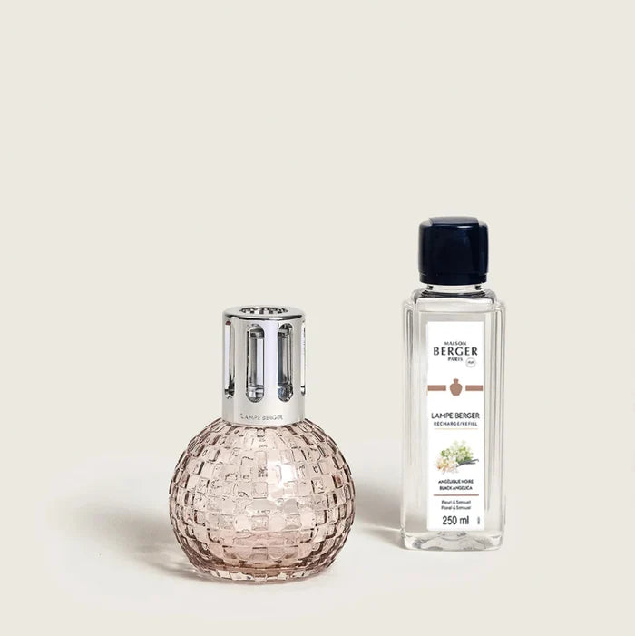 Pink glass diffuser and clear bottle with label on a light beige background