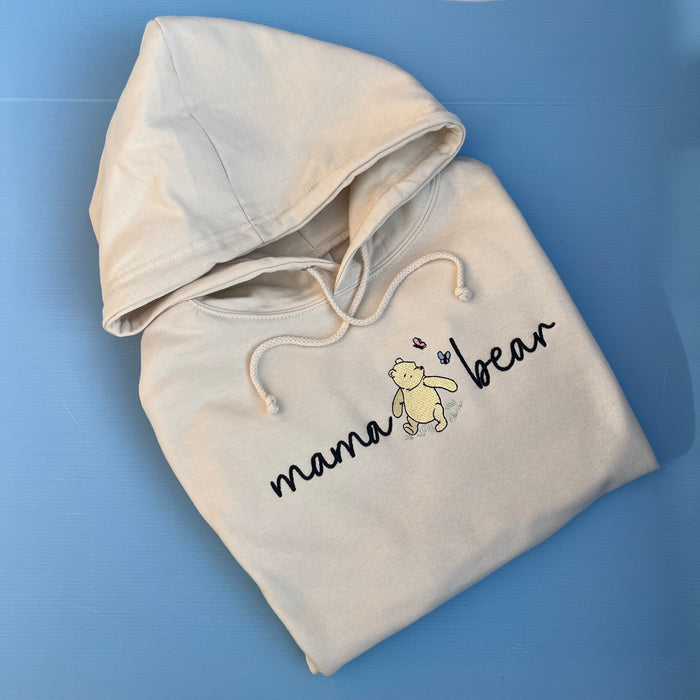 A beige hooded sweatshirt with 'mama bear' written on the front and an image of pooh bear.
