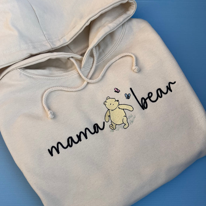 A beige hooded sweatshirt with 'mama bear' written on the front and an image of pooh bear.