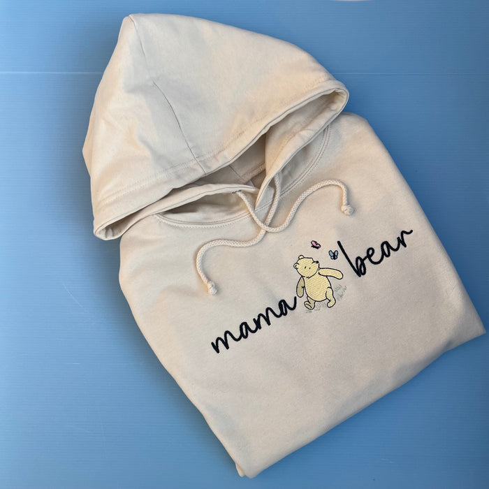 A beige hooded sweatshirt with 'mama bear' written on the front and an image of pooh bear.