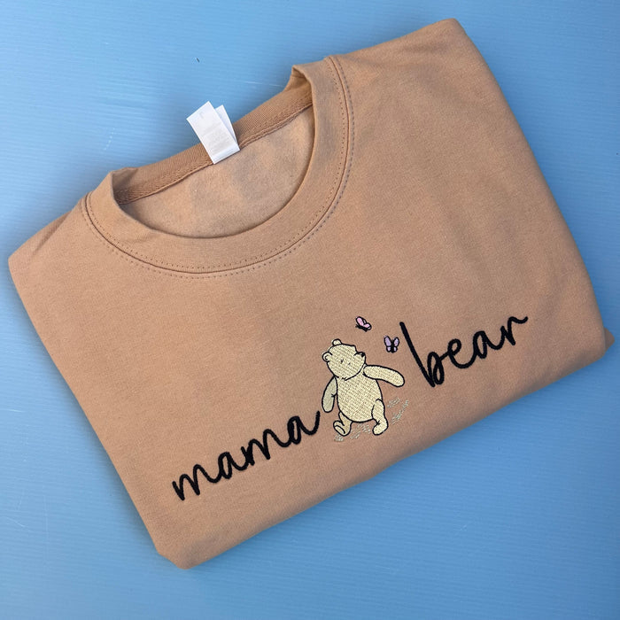 A beige sweatshirt with 'mama bear' written on the front and an image of pooh bear.
