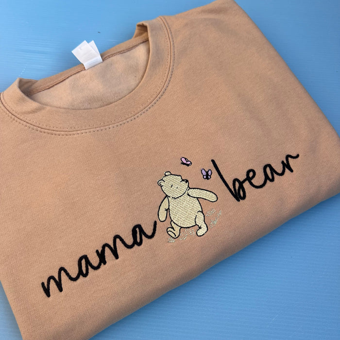 A beige sweatshirt with 'mama bear' written on the front and an image of pooh bear.