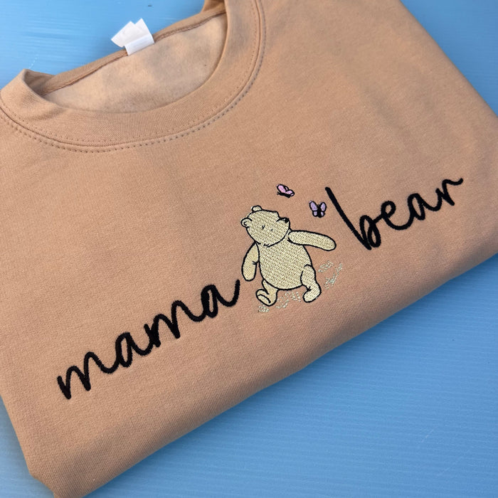 A beige sweatshirt with 'mama bear' written on the front and an image of pooh bear.