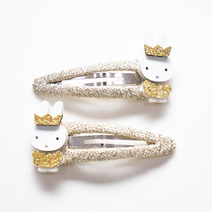 Two gold Miffy hair clips with crowns and dresses.