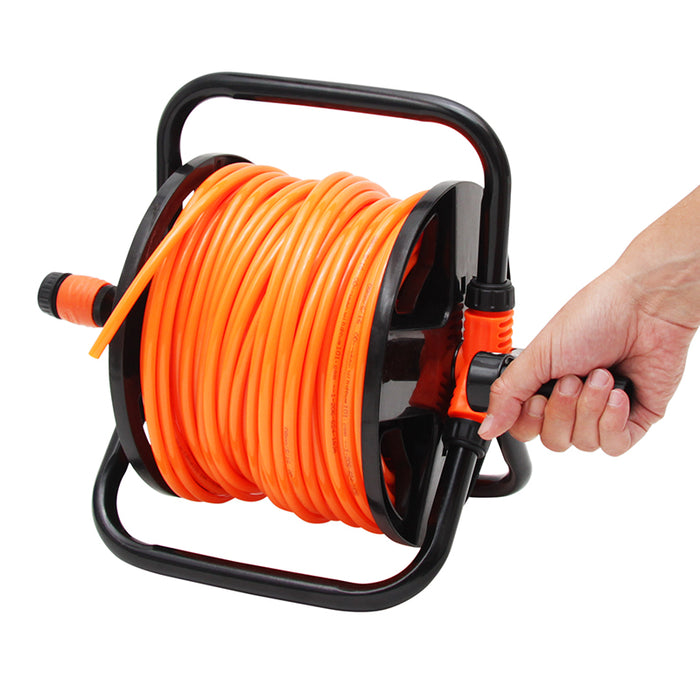 Orange garden hose coiled on a black reel with a hand gripping the handle against a white background