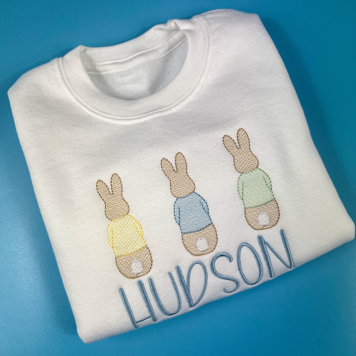 Close up of 3 bunnies embroidered on a white sweatshirt