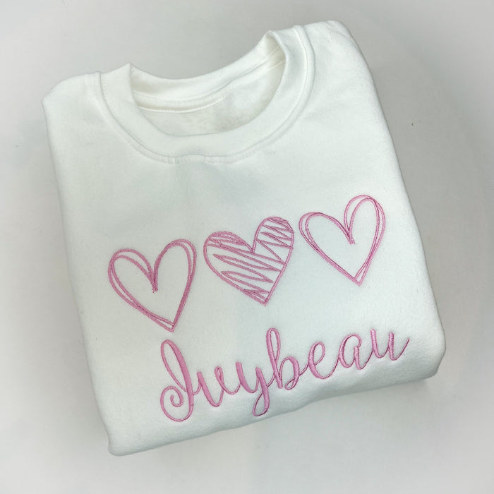 White crew neck sweatshirt with pink hearts and the name 'Julie' printed on the front.