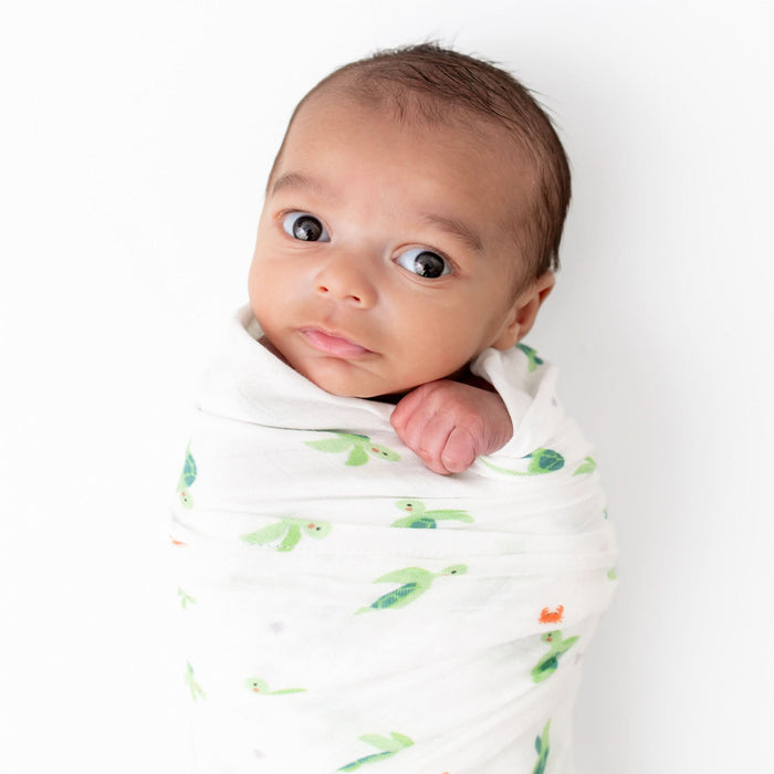 Baby wrapped in turtle muslin swaddle