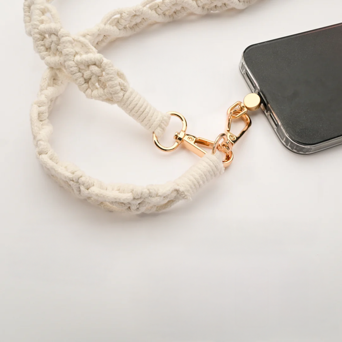 Natural-colored macramé crossbody strap with golden clips attached to an iPhone | Gifts against human trafficking